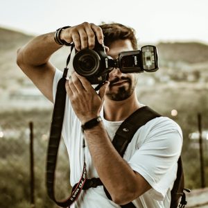 Photographer with camera and flash capturing the moment outdoors.